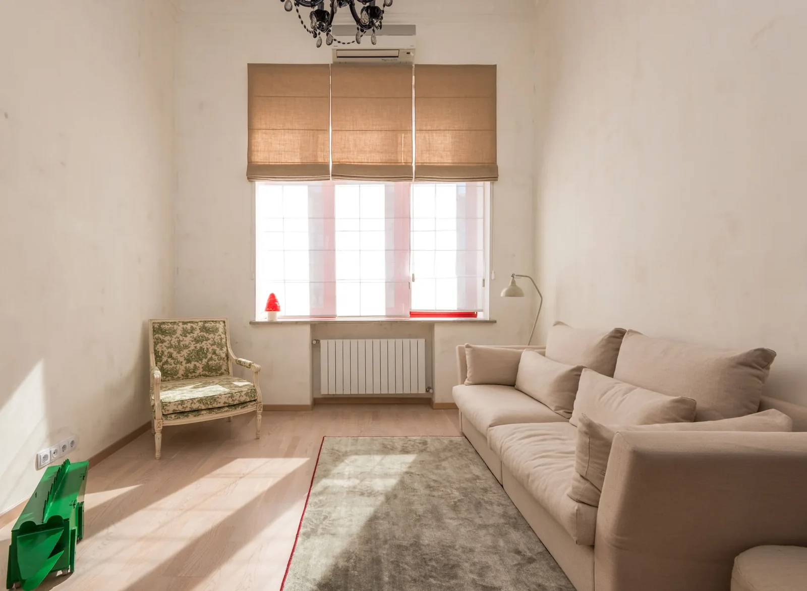 Sunlit sitting area with a beige sofa and a classic armchair.