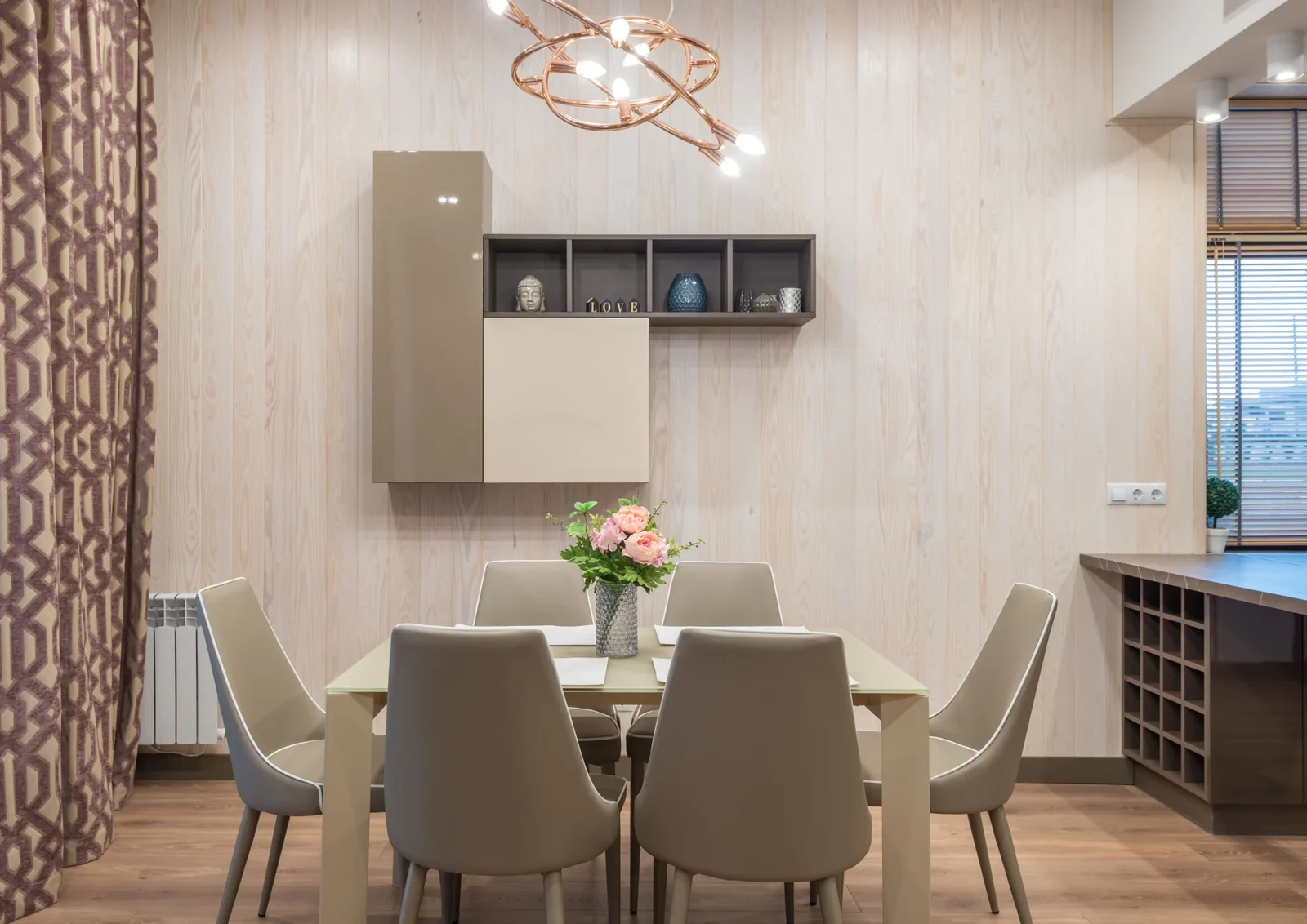 Dining table and upholstered chairs with flowers in a neutral interior.