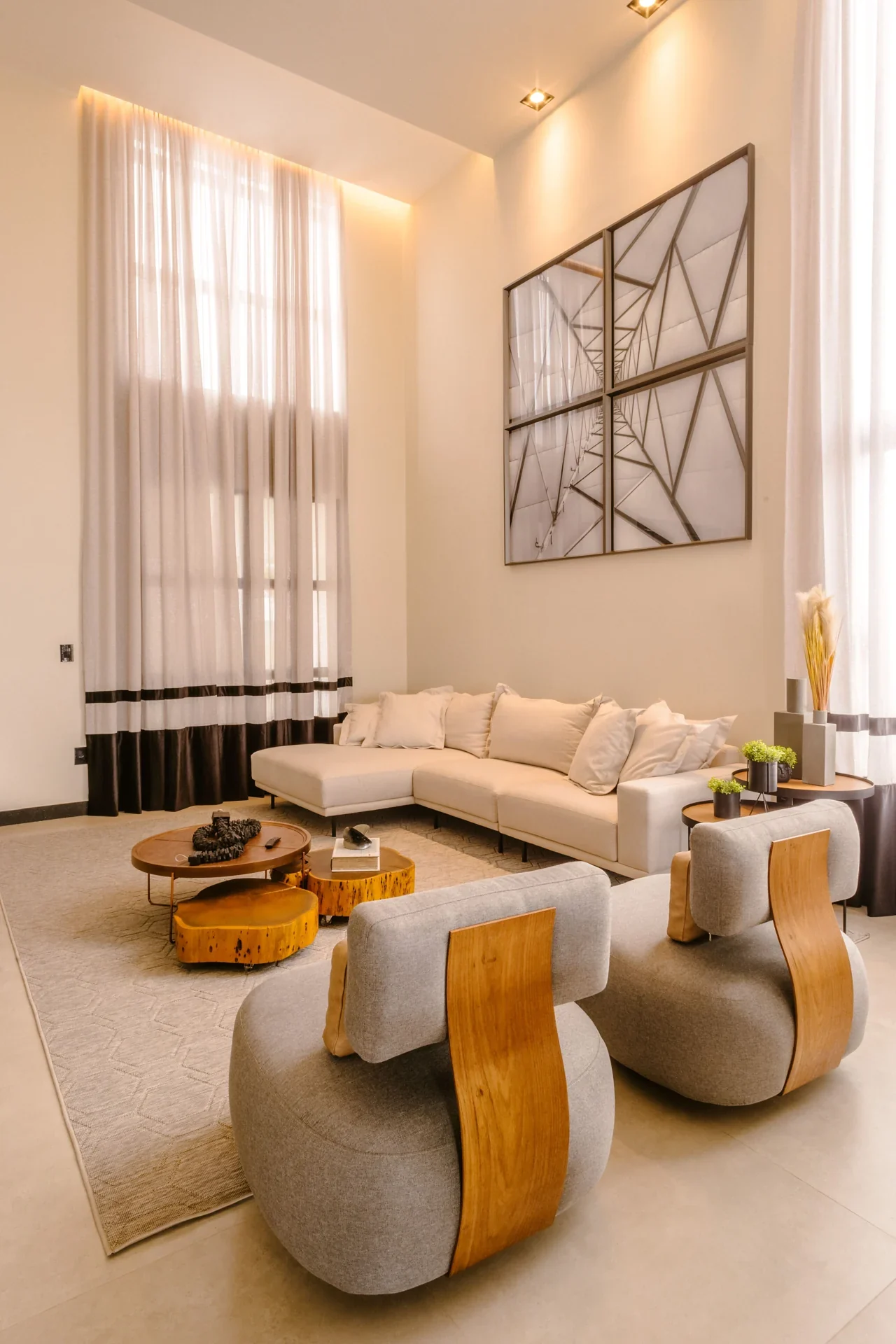 Living room with tall curtains, neutral sofas, and wooden tables.