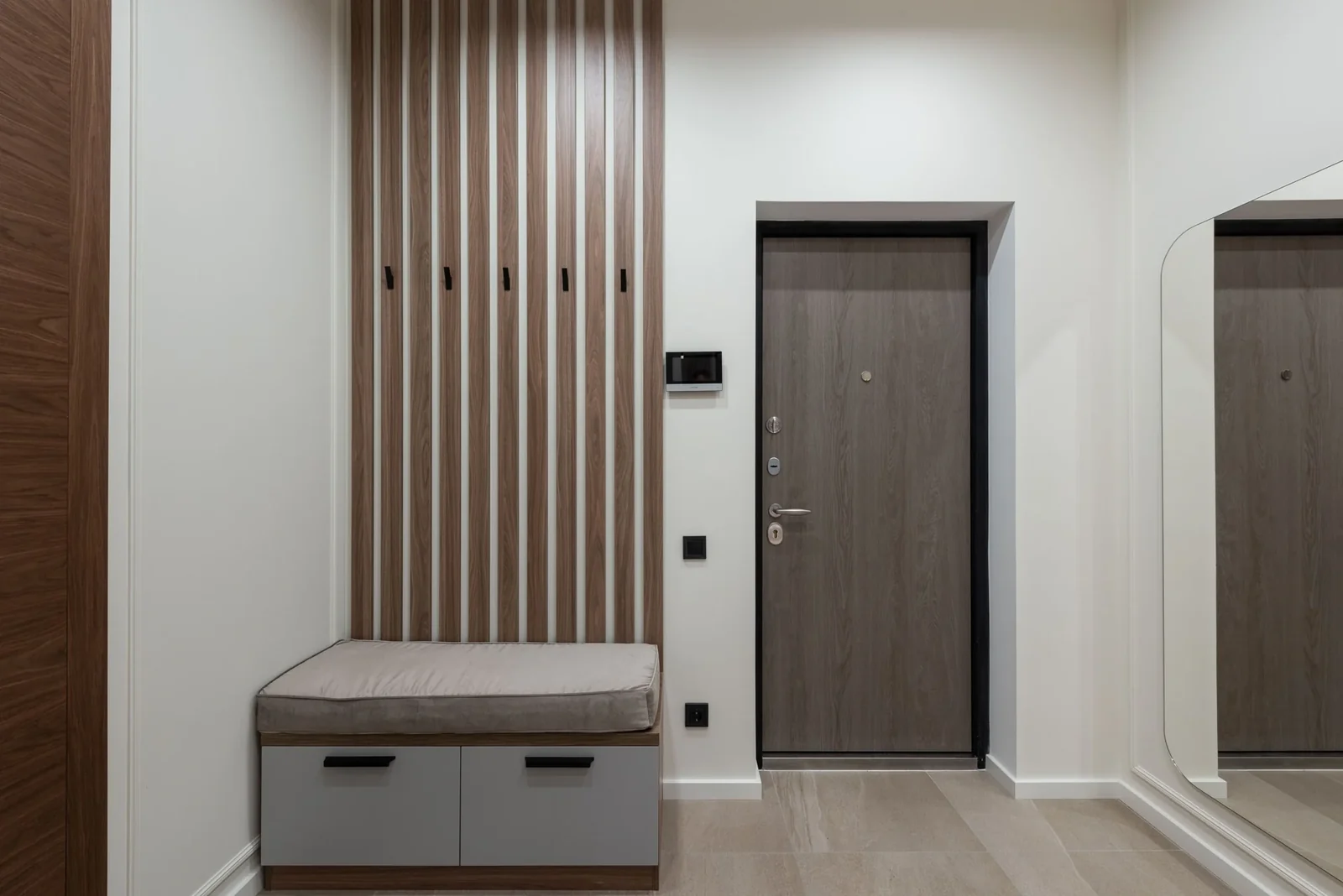 Home entrance with wooden panels, built-in seating and a large mirror.