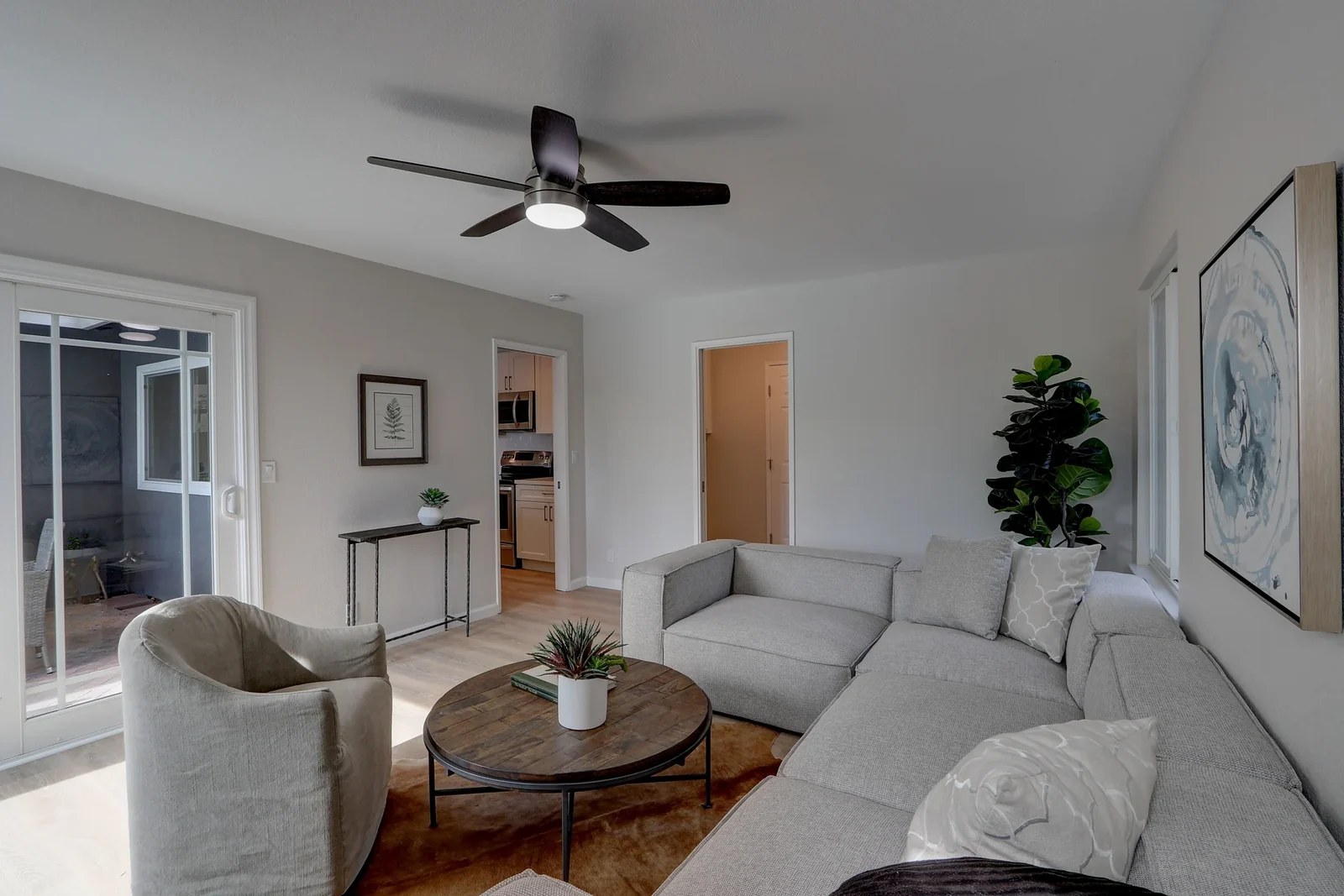 Living room with a sofa, armchairs, a wooden table and neutral decor.
