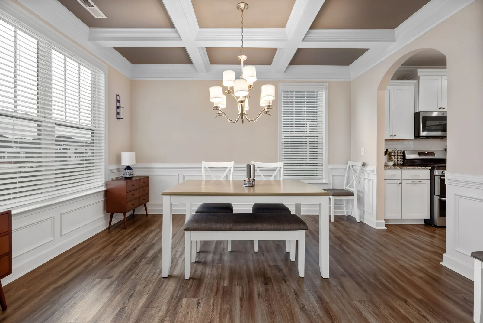 Dining area with a table, chairs, bench seating, and white wall panels.