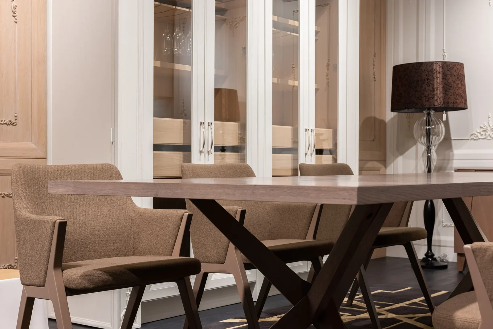Dining room with a long table, brown upholstered chairs, white cabinetry and a floor lamp.