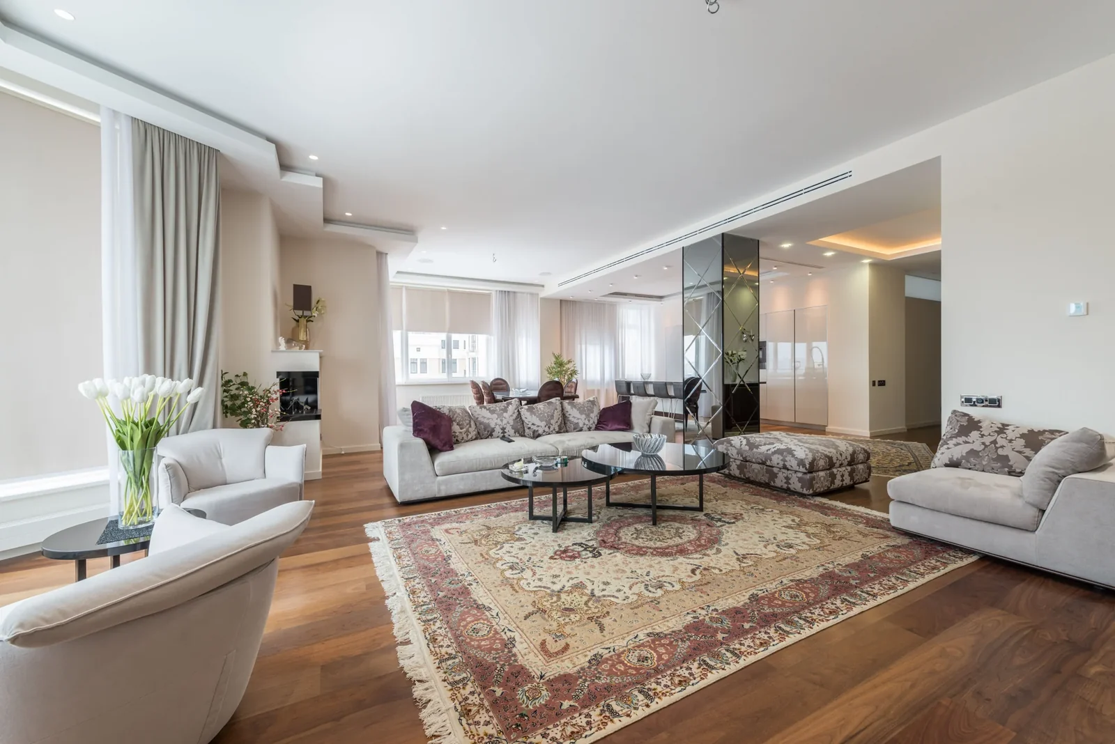 Living room with a sofa, upholstered armchairs, and a low table in daylight.