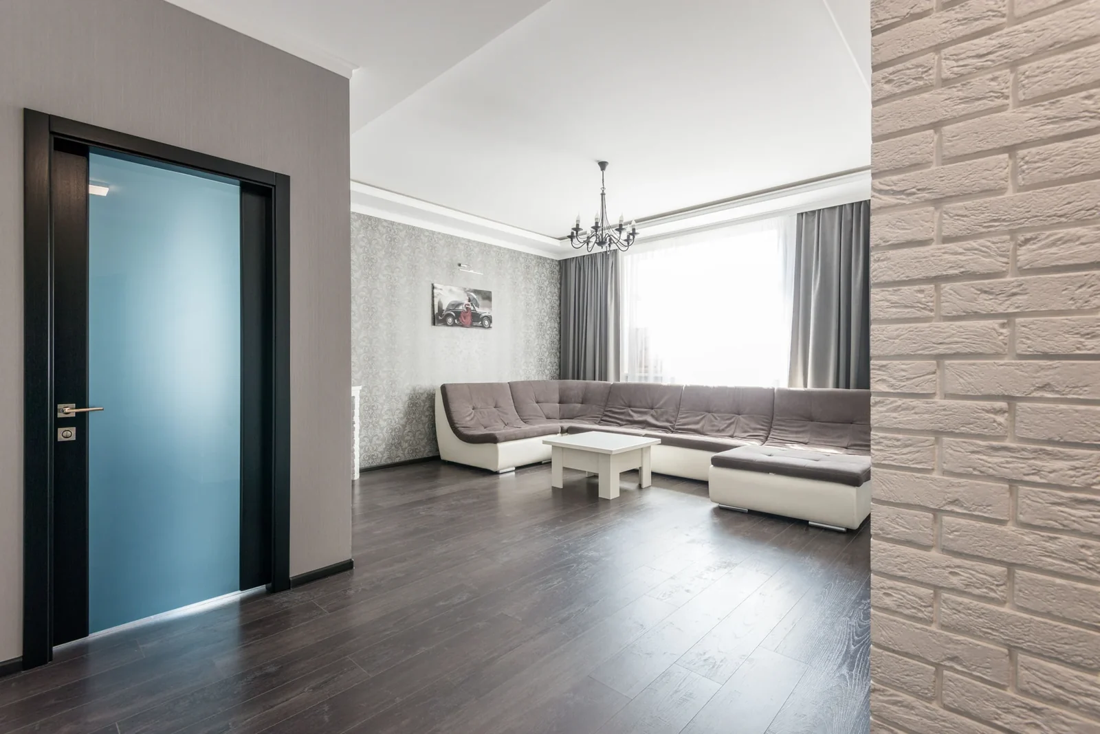 Modern living room with a large sectional sofa, low white table and wood flooring.
