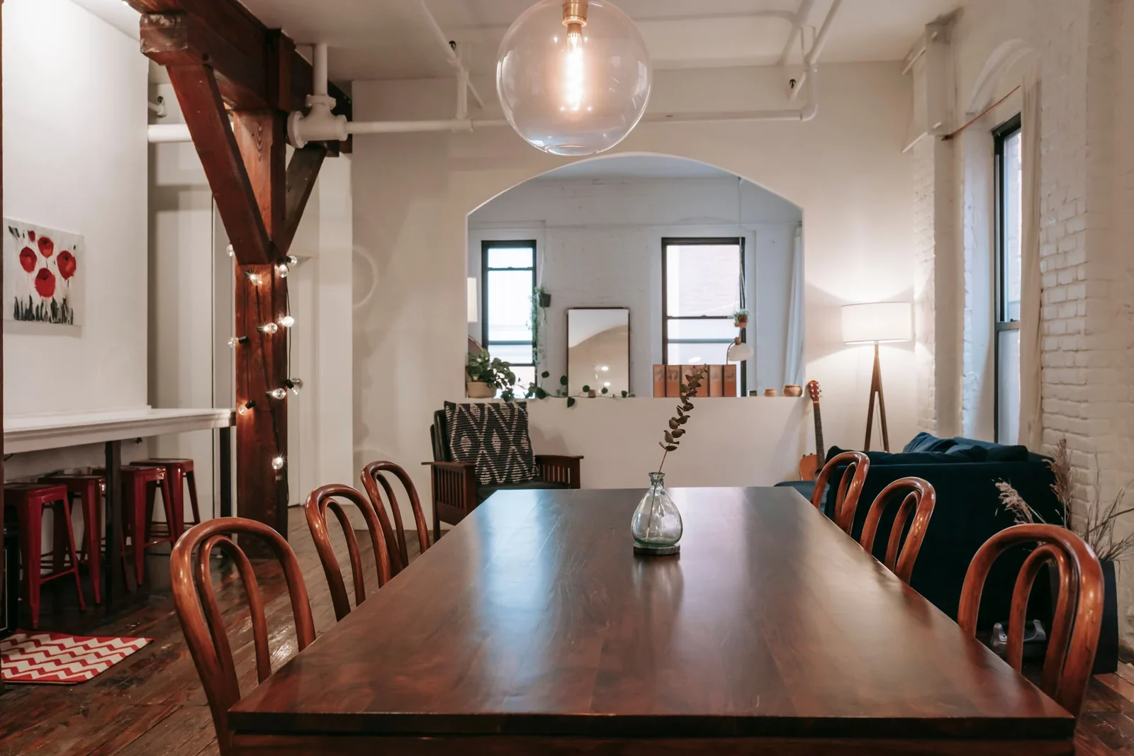 Wooden dining table and chairs in an open interior with a white brick wall.