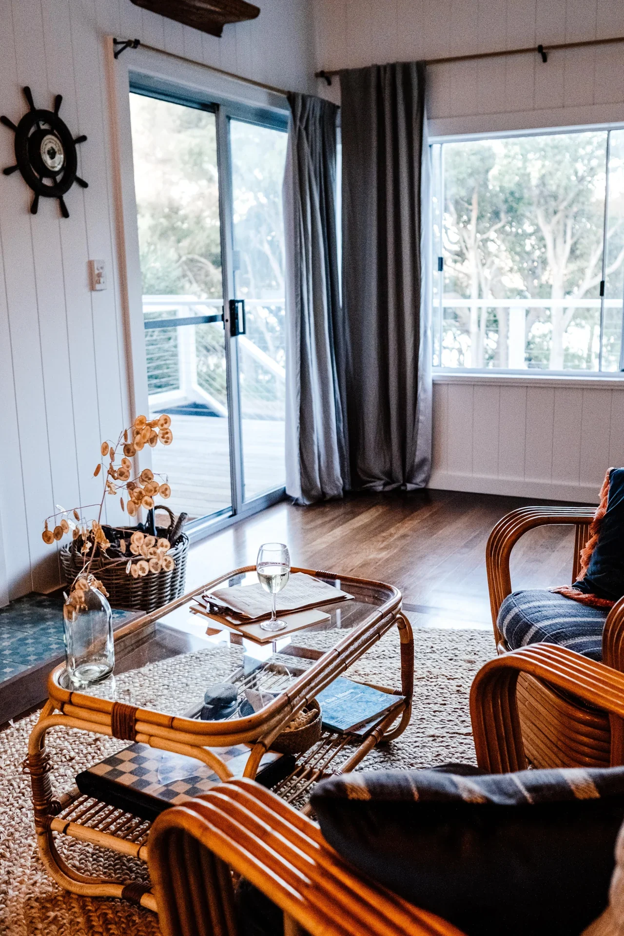 Living room with rattan furniture and glass doors opening toward a deck.
