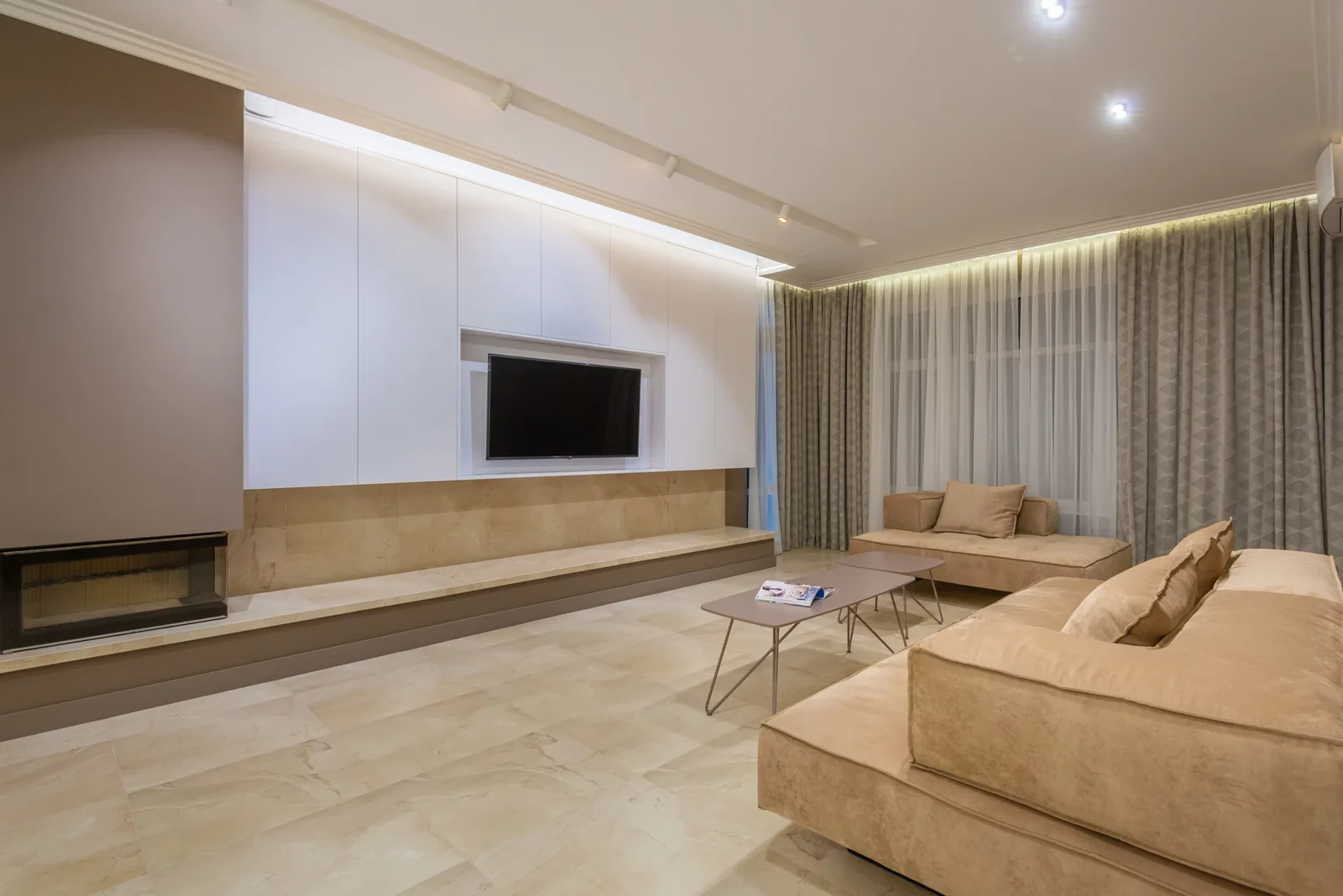 Large living room with beige sofas, a television and recessed lighting.