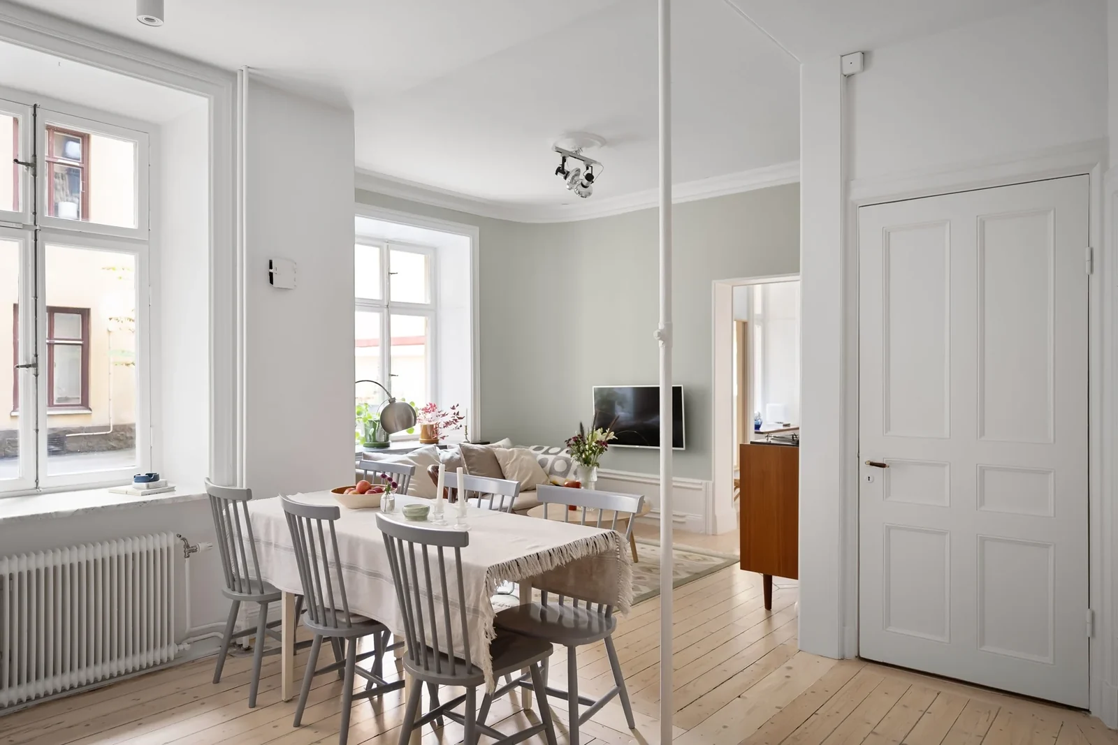 Living and dining area with white walls, wood flooring, and minimalist furniture.