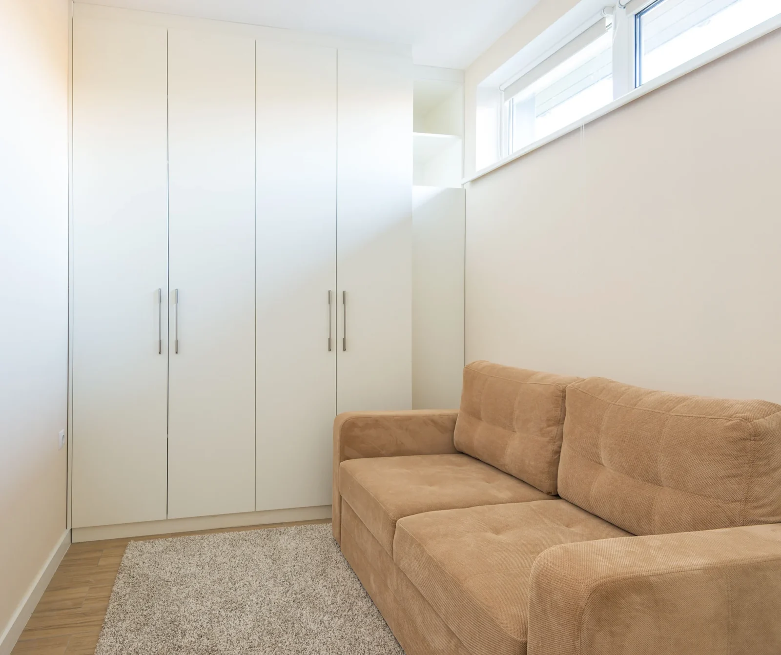 Beige couch beside white cabinetry in a bright modern living room.