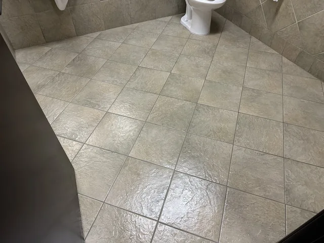 Commercial restroom tile and grout after cleaning: Lighter-looking tile and grout across the same restroom floor.
