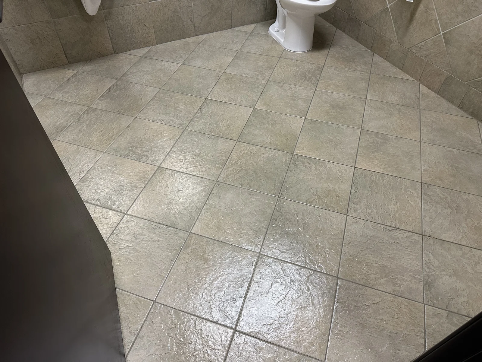Commercial restroom tile and grout after cleaning: Lighter-looking tile and grout across the same restroom floor.
