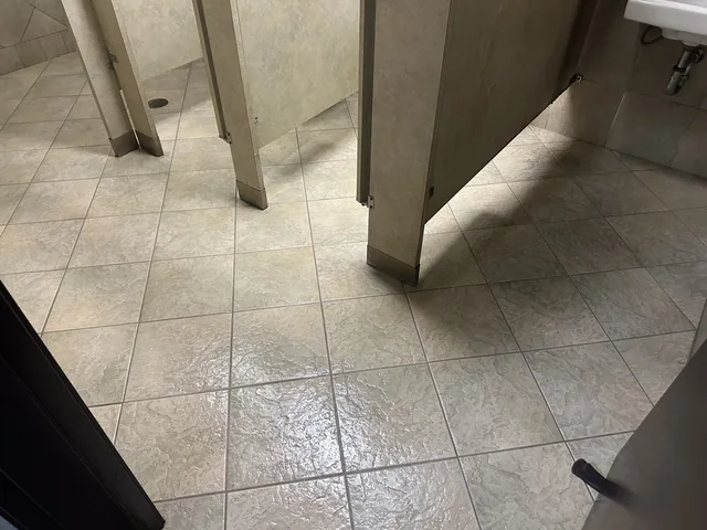 Commercial restroom tile and grout after cleaning: The same partition layout with visibly lighter tile and grout.