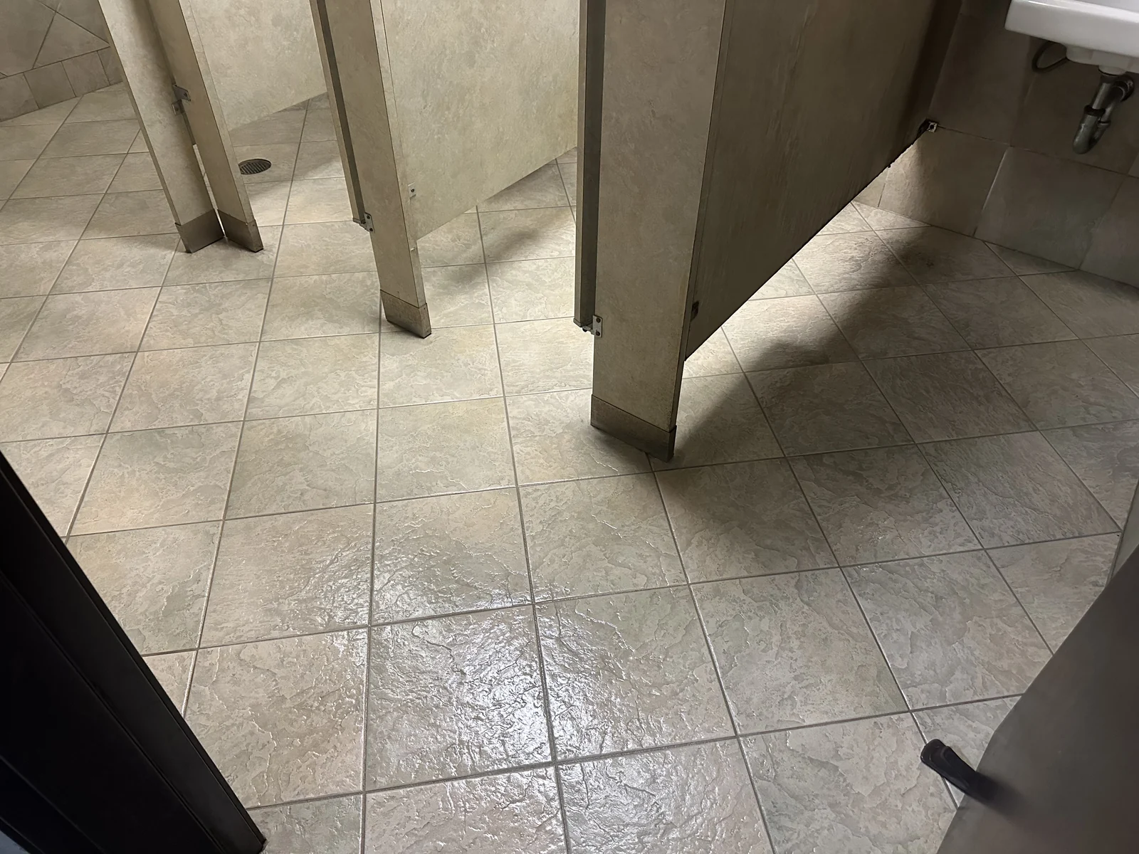 Commercial restroom tile and grout after cleaning: The same partition layout with visibly lighter tile and grout.