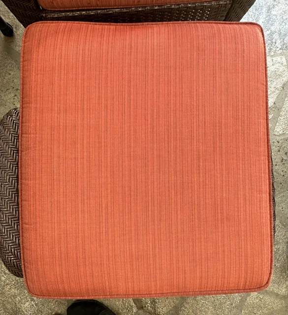 Coral upholstered seat cushion after cleaning: The same cushion with fewer visible marks and a more even-looking color.