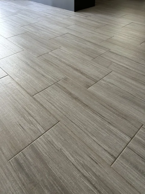 Gray rectangular floor tile and grout after cleaning: The same layout with lighter-looking grout between the rectangular tiles.