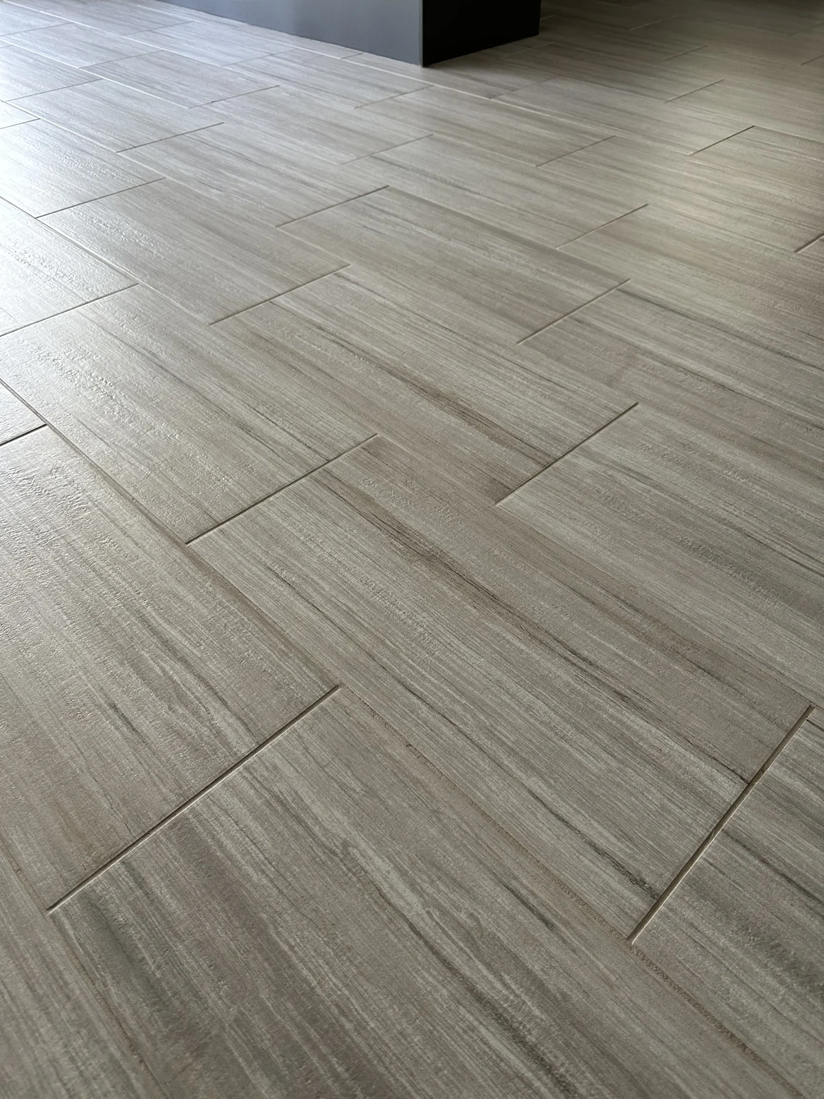 Gray rectangular floor tile and grout after cleaning: The same layout with lighter-looking grout between the rectangular tiles.