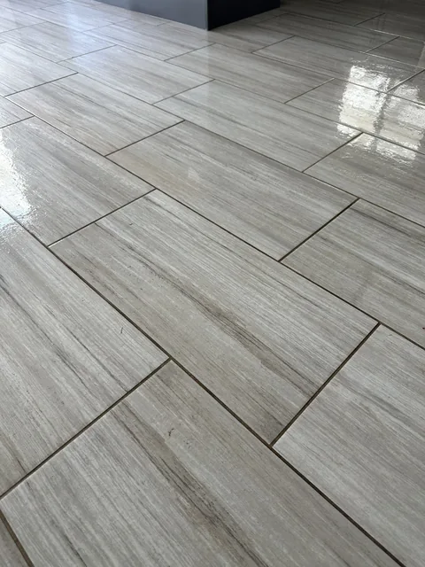 Gray rectangular floor tile and grout before cleaning: Dark joints interrupting the pattern of a gray plank-shaped tile floor.