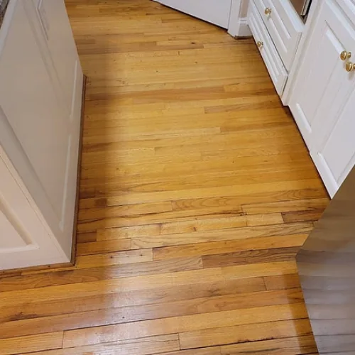 Hardwood kitchen floor after cleaning: The same board pattern with a lighter, more consistent appearance.