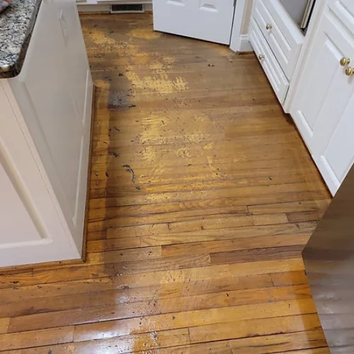 Hardwood kitchen floor before cleaning: Dark, uneven-looking patches across the kitchen’s wood floorboards.