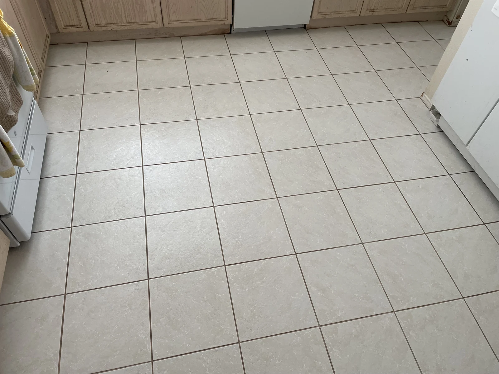 Square floor tile and grout after cleaning: Lighter-looking grout lines and a more consistent appearance across the kitchen tile.