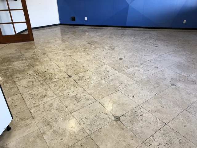 Decorative tile floor before cleaning: Visible soil and a dull appearance across a large tiled room.