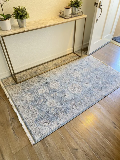 Blue and cream patterned area rug after cleaning: The matching rug photographed back in an entryway, with its blue and cream pattern in view. The setting and lighting differ.