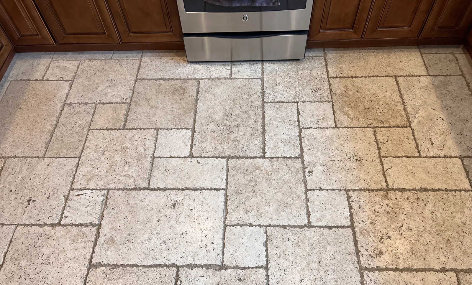 Patterned floor tile and grout before cleaning: Dark grout lines and uneven-looking soil across a kitchen’s patterned tile.