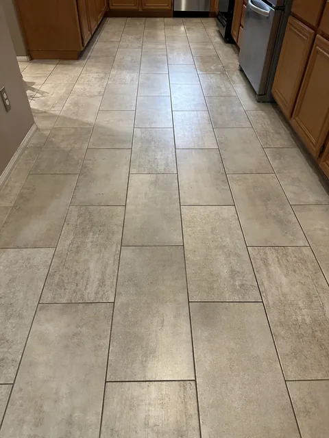 Rectangular kitchen tile and grout before cleaning: Dark grout lines around the long rectangular tiles in a kitchen walkway.