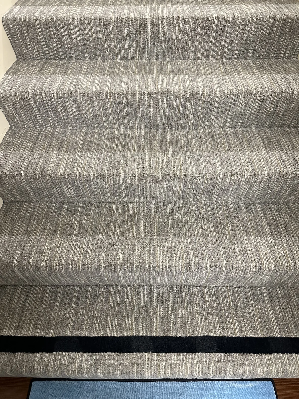 Striped stair carpet after cleaning: The same striped staircase with fewer visible specks across the treads.