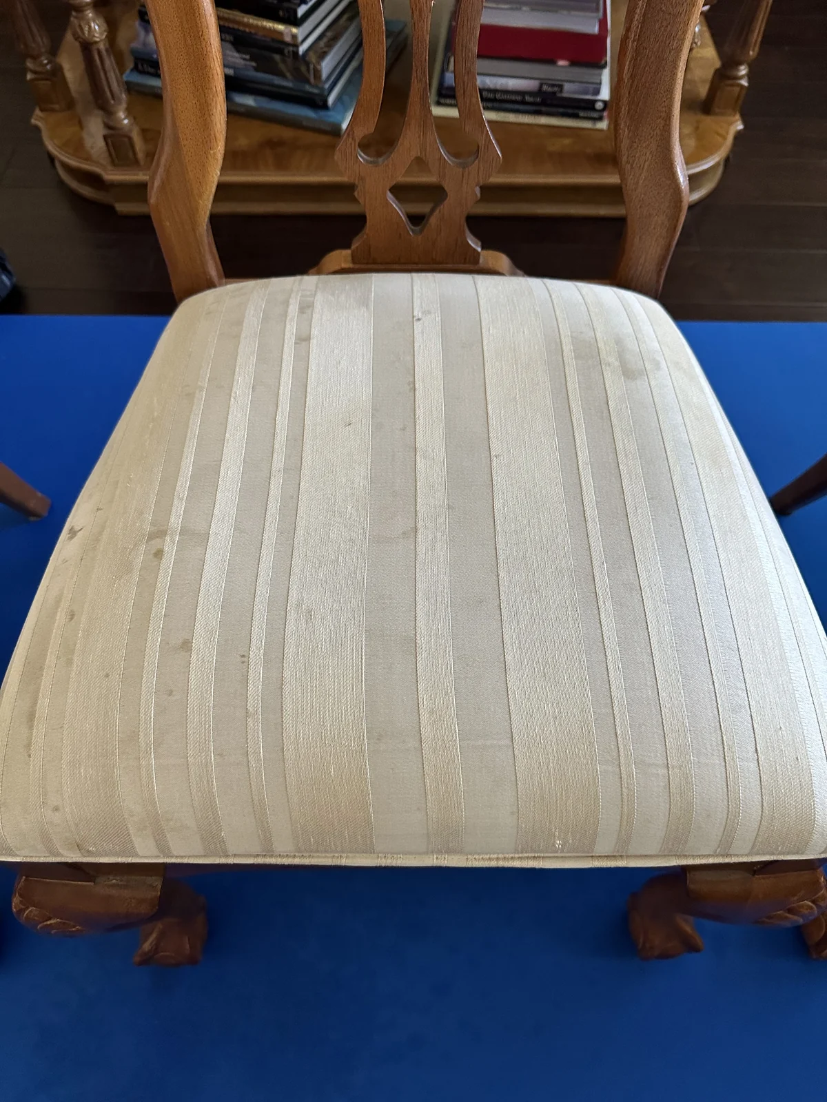 Striped upholstered dining-chair seat before cleaning: Small dark marks on the pale striped upholstery of a dining chair.