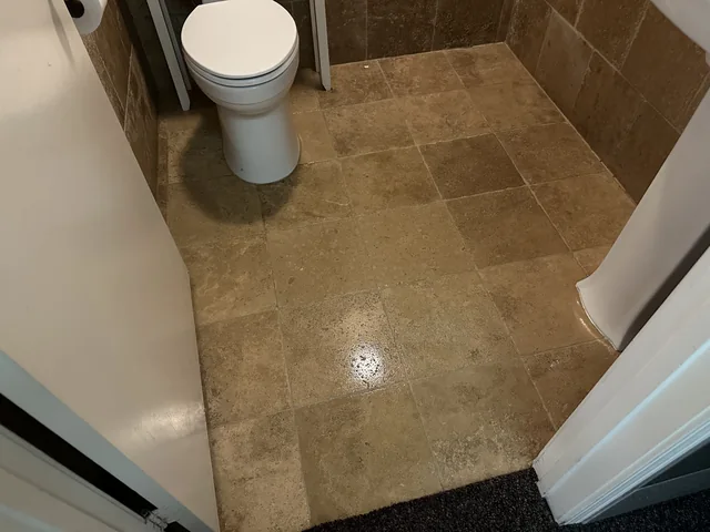 Tan bathroom floor tile and grout after cleaning: The same tile layout with a more even appearance and less visible surface soiling.