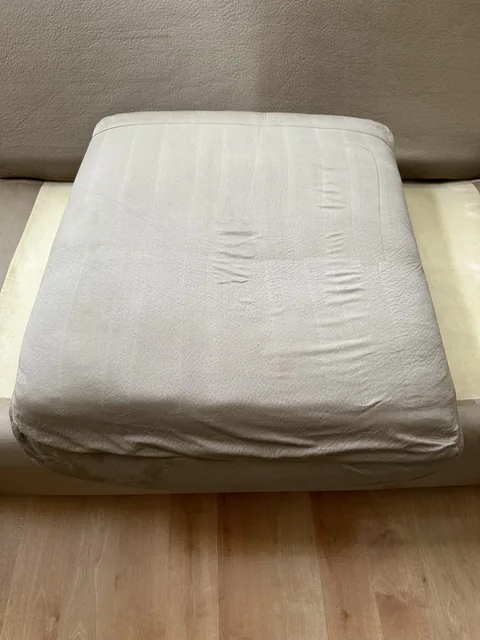 Upholstered ottoman after cleaning: A lighter, more even-looking fabric surface on the same piece.