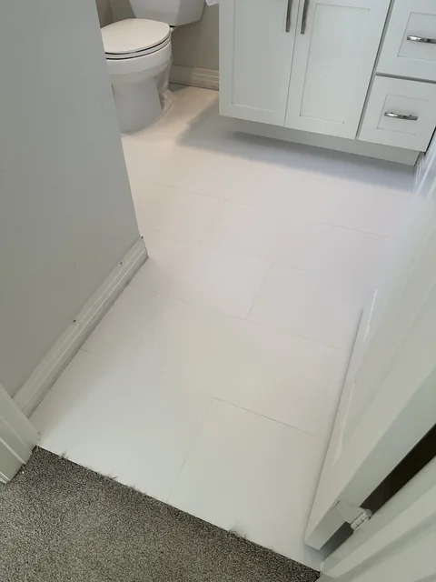 White rectangular bathroom tile and grout after cleaning: Paler-looking grout between the tiles beside the same vanity and toilet.