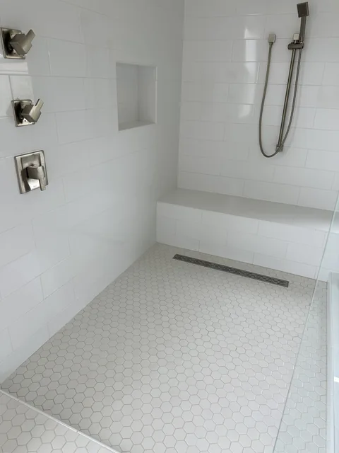 Shower wall tile, floor tile and grout after cleaning: The matching shower enclosure, bench and drain with paler-looking floor joints.