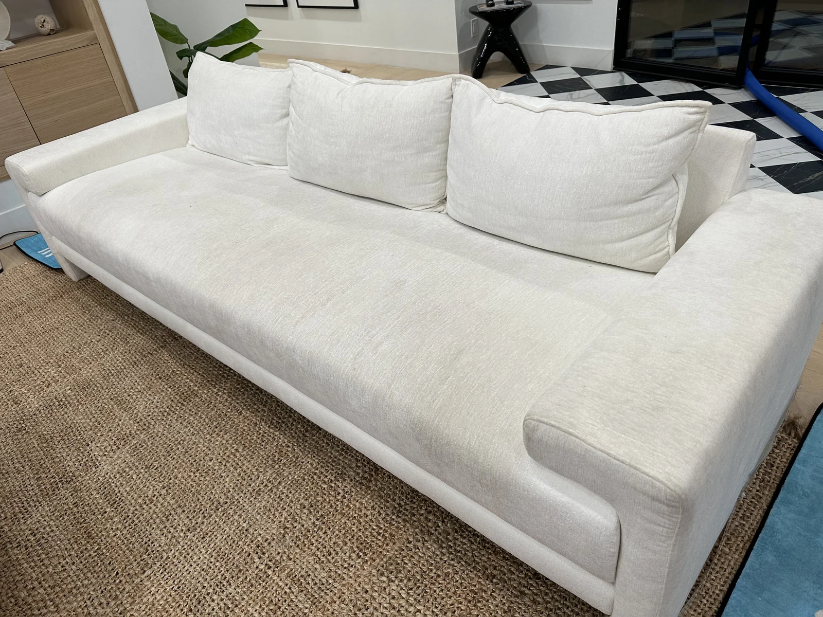 Light upholstered sofa before cleaning: Visible spots and yellowish patches on a light sofa’s long seat cushion.