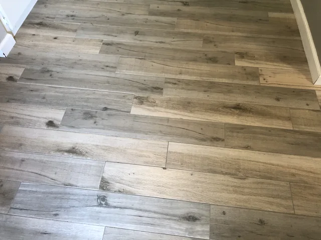 Wood-look tile and grout after cleaning: The same grain pattern with lighter-looking joints and fewer visible dark marks.