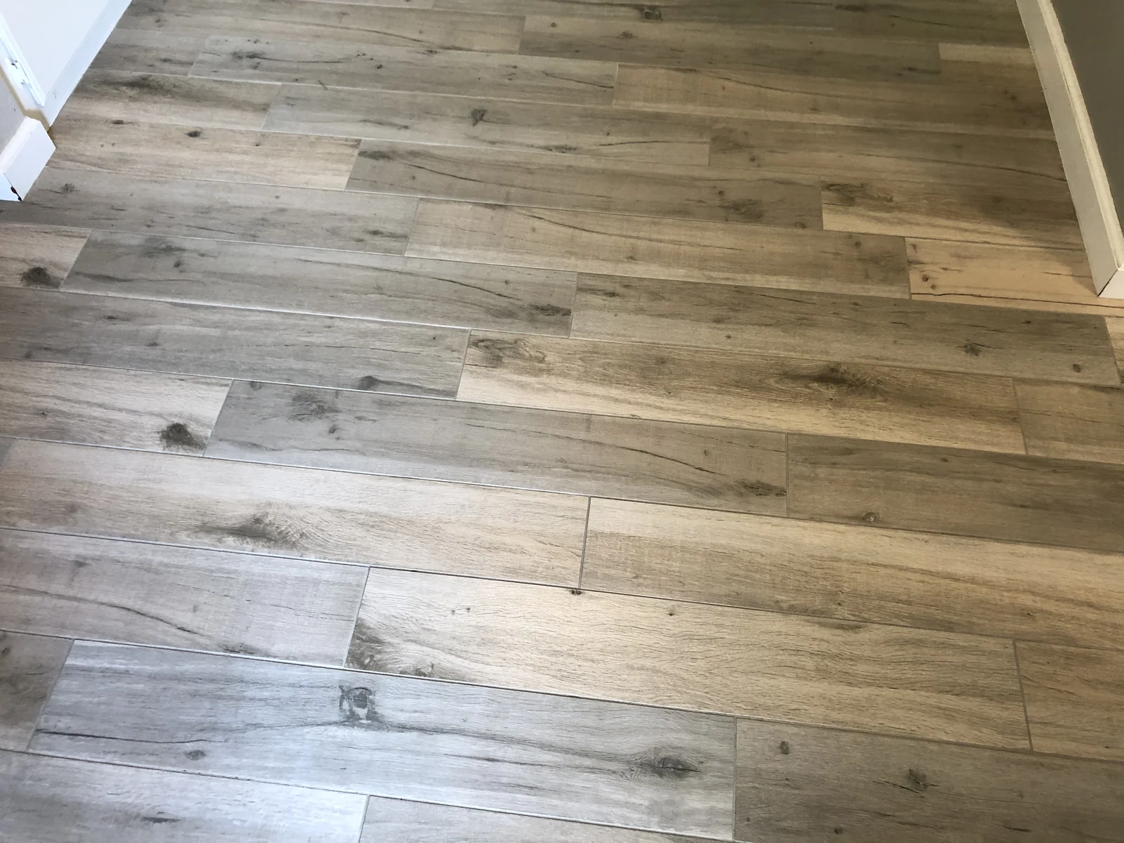 Wood-look tile and grout after cleaning: The same grain pattern with lighter-looking joints and fewer visible dark marks.